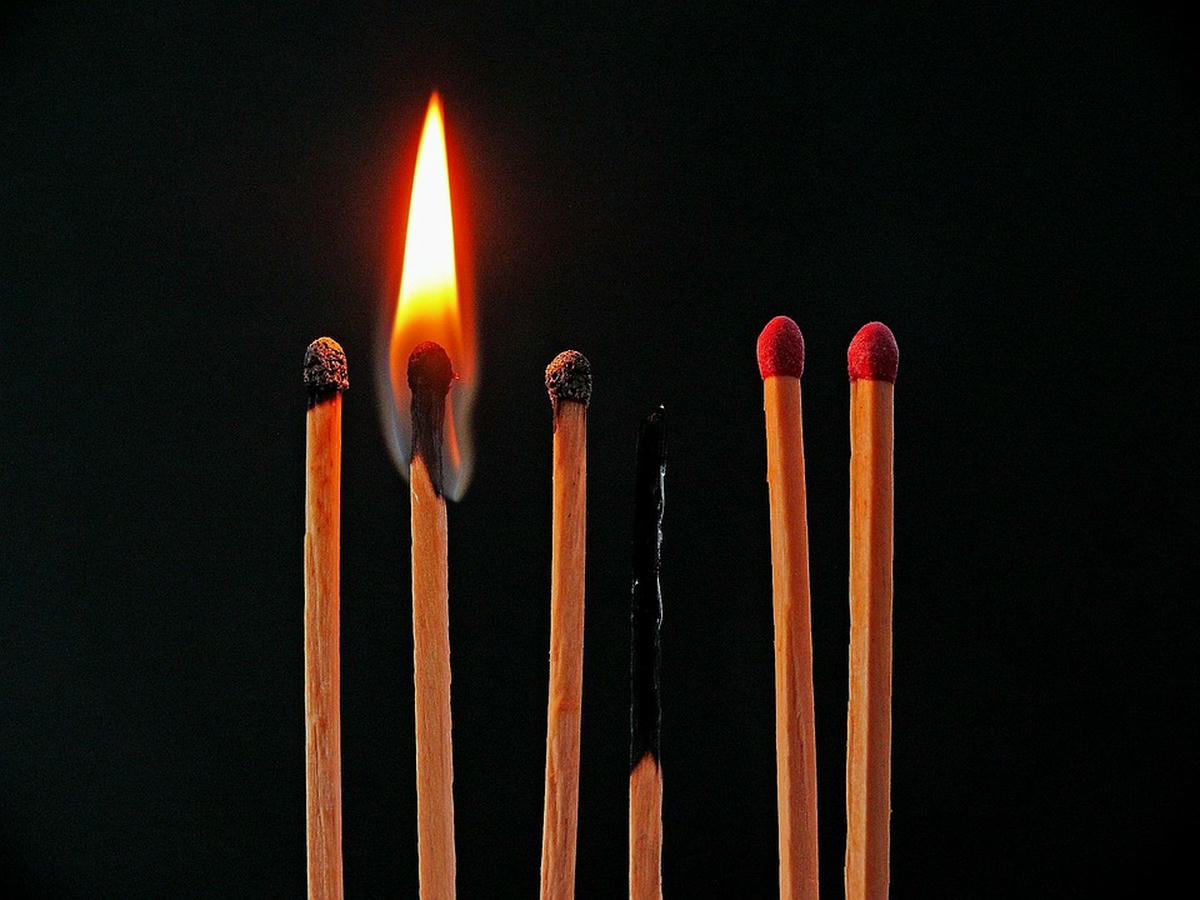 Brandende en opgebrande lucifers naast onbeschadigde lucifers, symbool voor burn-out, uitputting en kwetsbaarheid in relaties.