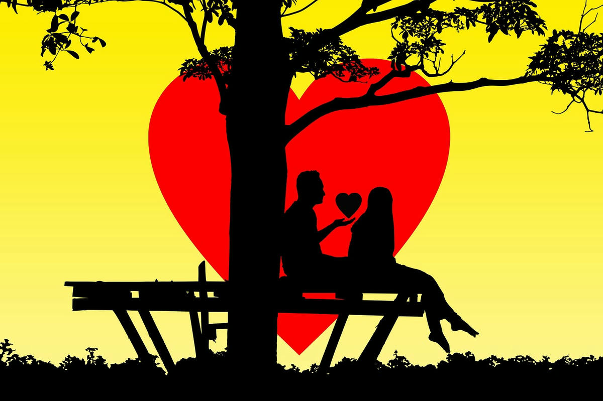 Silhouet van een koppel op een bank onder een boom met een groot rood hart op de achtergrond, symbool voor liefde en romantiek.