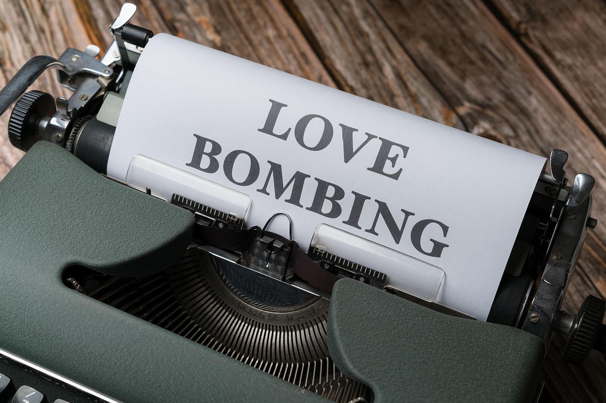Vintage typemachine met het woord “Love Bombing” op papier – symbool voor moderne datingtrends en nieuwe relatiebegrippen zoals No-Habiting, Rejuve-dating en meer.