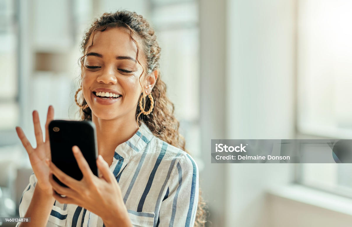 Vrolijke jonge vrouw die glimlachend op haar smartphone kijkt, symbool voor verbinding en relaties