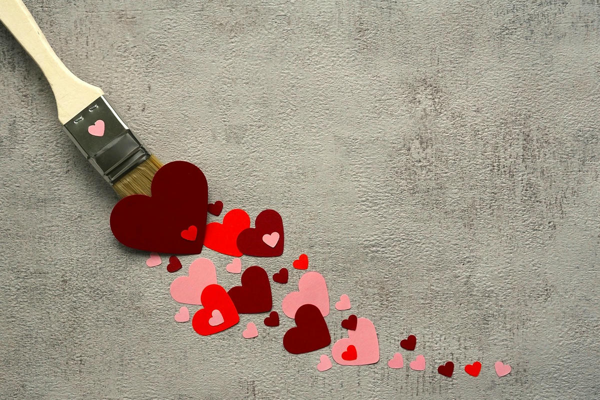 Verfborstel die rode hartjes schildert als symbool voor liefde, persoonlijke groei en het opbouwen van zelfvertrouwen in relaties.